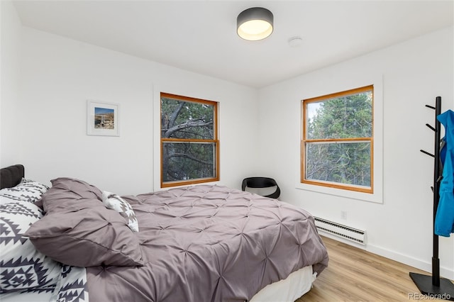 236 Harris Dr, Idaho Springs, CO 80452 - bedroom with a baseboard heating unit, multiple windows, light wood-style flooring, and baseboards