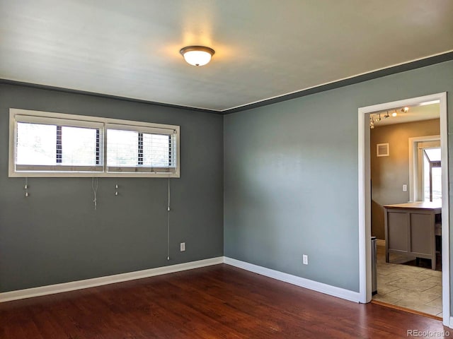 unfurnished room with dark wood finished floors and baseboards