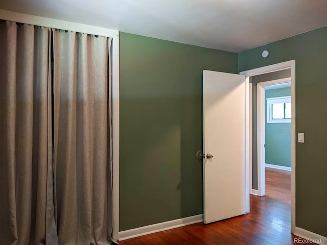 unfurnished bedroom with dark wood finished floors and baseboards