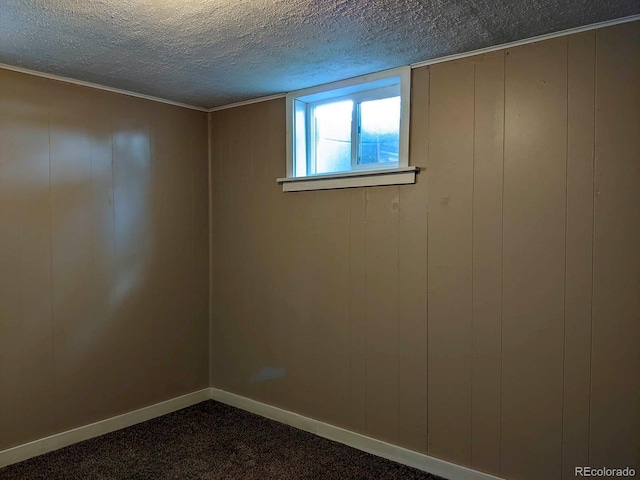 below grade area with a textured ceiling, dark colored carpet, and baseboards