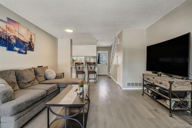 3618 Queen Anne Way, Colorado Springs, CO 80917 - living room with visible vents, baseboards, a textured ceiling, and wood finished floors