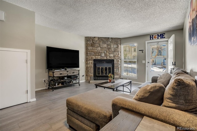 3618 Queen Anne Way, Colorado Springs, CO 80917 - living room with baseboards, a textured ceiling, wood finished floors, and a stone fireplace
