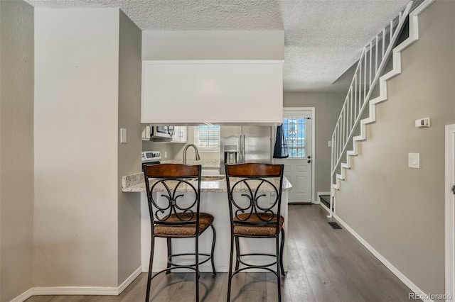 3618 Queen Anne Way, Colorado Springs, CO 80917 - kitchen with a textured ceiling, dark wood-style floors, a breakfast bar, and stainless steel appliances