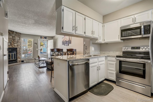 3618 Queen Anne Way, Colorado Springs, CO 80917 - kitchen featuring appliances with stainless steel finishes, light stone countertops, a sink, white cabinets, and light wood-style floors