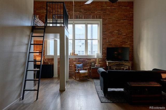 living room featuring ceiling fan, brick wall, and wood-type flooring