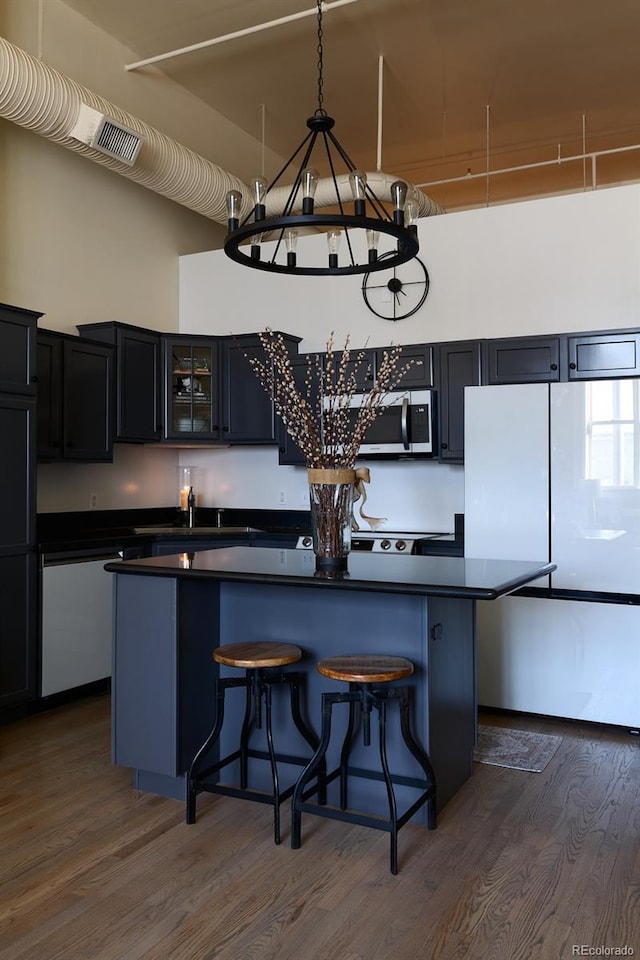 kitchen featuring a breakfast bar area, dark hardwood / wood-style floors, white fridge, and a kitchen island