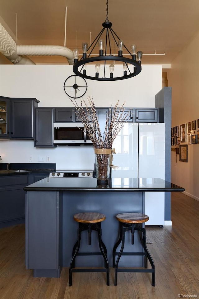 kitchen with sink, a kitchen island, dark hardwood / wood-style flooring, hanging light fixtures, and a breakfast bar area