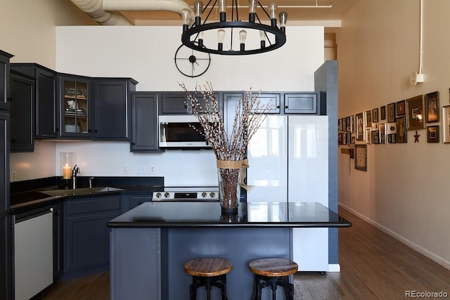 kitchen featuring dark hardwood / wood-style floors, sink, a center island, a notable chandelier, and appliances with stainless steel finishes