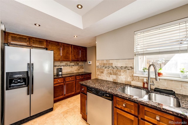 kitchen featuring appliances with stainless steel finishes, tasteful backsplash, dark stone countertops, and sink