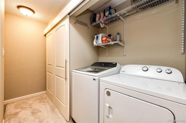 washroom featuring separate washer and dryer, a textured ceiling, and light carpet