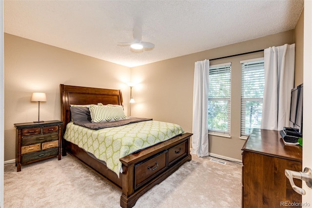 bedroom with ceiling fan, light carpet, and a textured ceiling