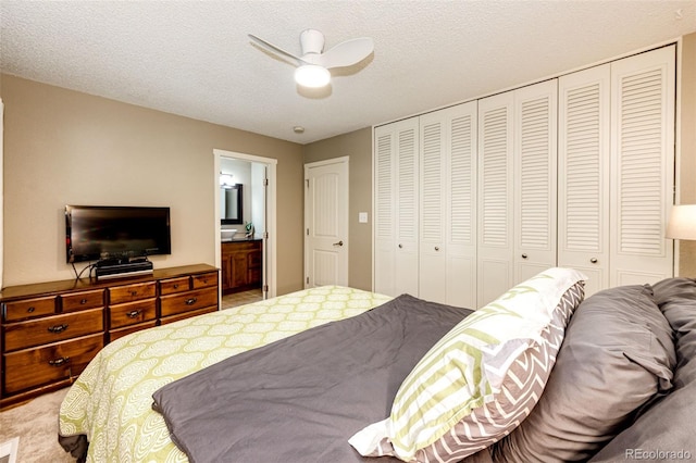 bedroom with carpet flooring, ensuite bath, ceiling fan, and a textured ceiling