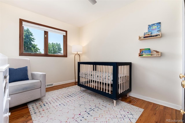 5067 S Mabre Ct, Littleton, CO 80123 - bedroom featuring wood finished floors and a crib