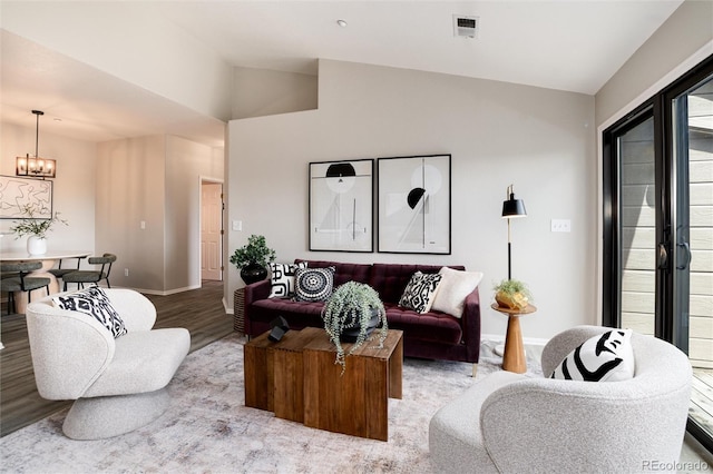 living area featuring lofted ceiling, wood finished floors, a chandelier, and baseboards