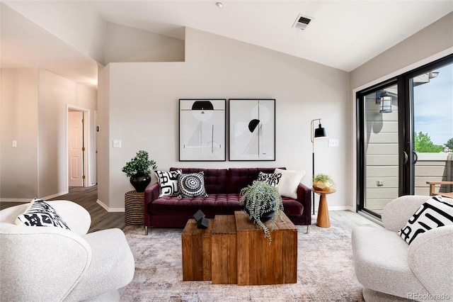 living room featuring lofted ceiling, wood finished floors, and baseboards