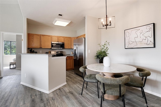 kitchen with stainless steel appliances, light wood-style flooring, a chandelier, breakfast area, and light countertops