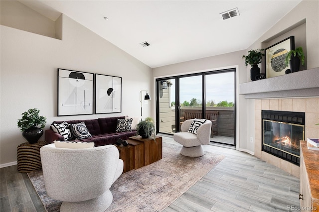 7408 S Alkire St Unit 301, Littleton, CO 80127 - living room featuring light wood-style floors, a tiled fireplace, baseboards, and high vaulted ceiling