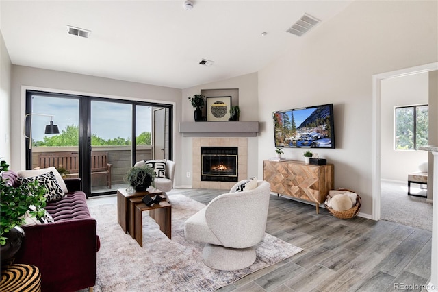 7408 S Alkire St Unit 301, Littleton, CO 80127 - living room with a tiled fireplace, light wood finished floors, plenty of natural light, lofted ceiling, and baseboards