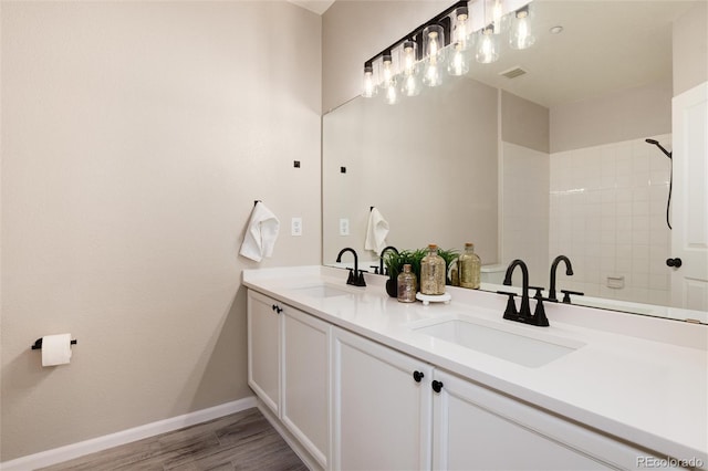 7408 S Alkire St Unit 301, Littleton, CO 80127 - bathroom featuring double vanity, wood finished floors, baseboards, and a tile shower