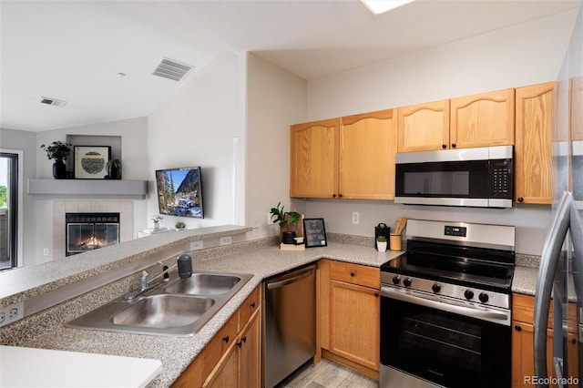 7408 S Alkire St Unit 301, Littleton, CO 80127 - kitchen with stainless steel appliances, a sink, vaulted ceiling, light countertops, and a fireplace