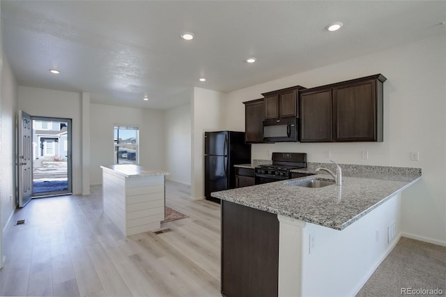 kitchen with black appliances, sink, light stone countertops, dark brown cabinets, and kitchen peninsula