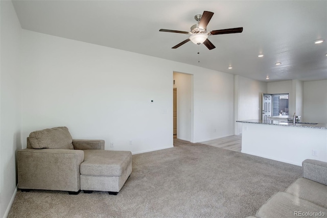 carpeted living room featuring ceiling fan and sink