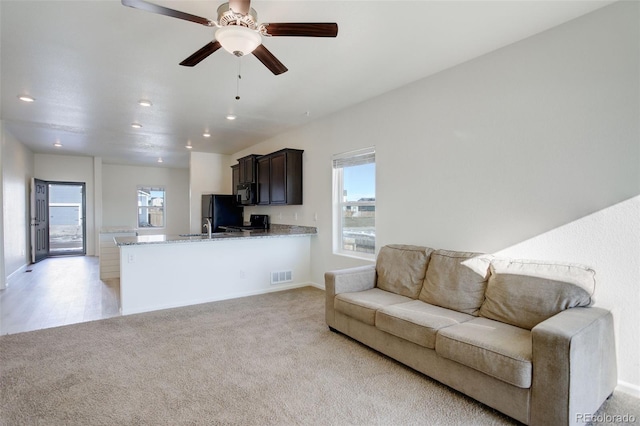 living room with ceiling fan, a healthy amount of sunlight, and light colored carpet