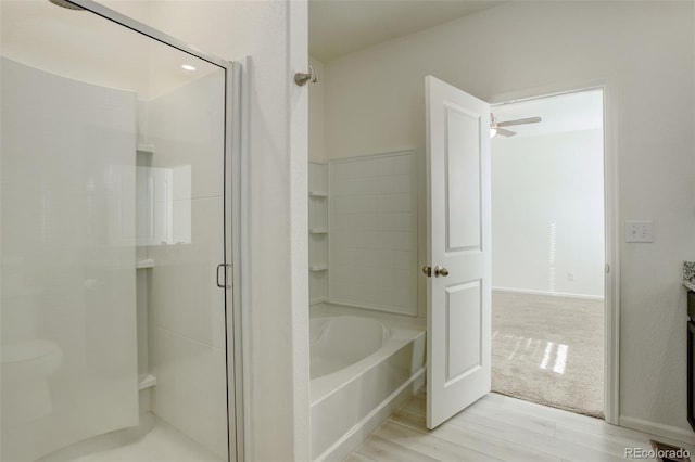 bathroom featuring ceiling fan, wood-type flooring, and plus walk in shower