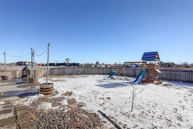 yard covered in snow featuring a playground