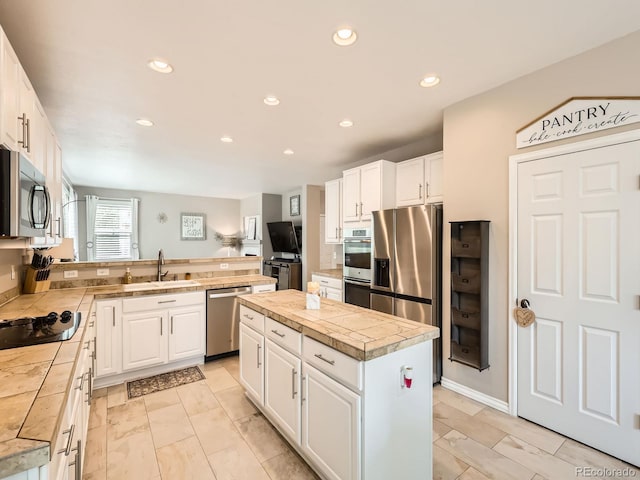8010 Raspberry Dr, Frederick, CO 80504 - kitchen with appliances with stainless steel finishes, a sink, white cabinetry, a peninsula, and a kitchen island