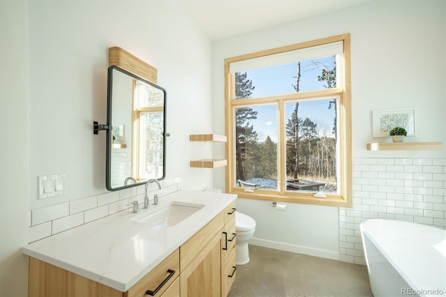 bathroom with vanity, toilet, and a tub