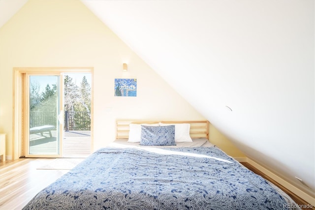 bedroom with access to exterior, hardwood / wood-style flooring, and lofted ceiling