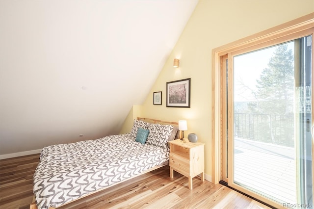 bedroom with access to outside, vaulted ceiling, and hardwood / wood-style flooring