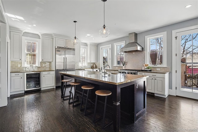201 S Lafayette St, Denver, CO 80209 - kitchen with beverage cooler, wall chimney exhaust hood, stainless steel built in refrigerator, recessed lighting, and backsplash