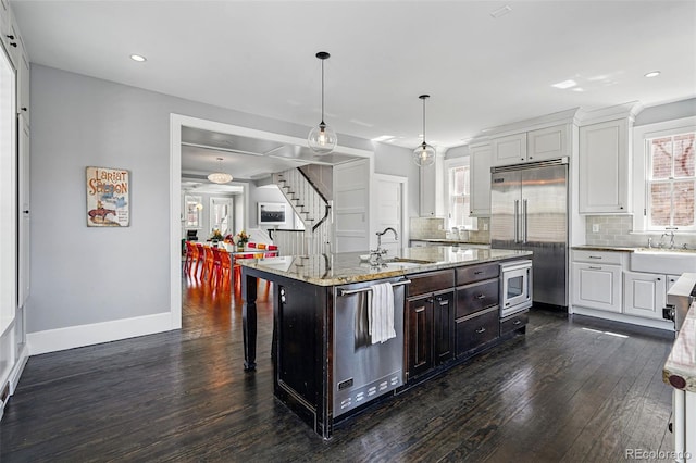 201 S Lafayette St, Denver, CO 80209 - kitchen with built in appliances, dark wood-style flooring, white cabinets, decorative backsplash, and light stone counters
