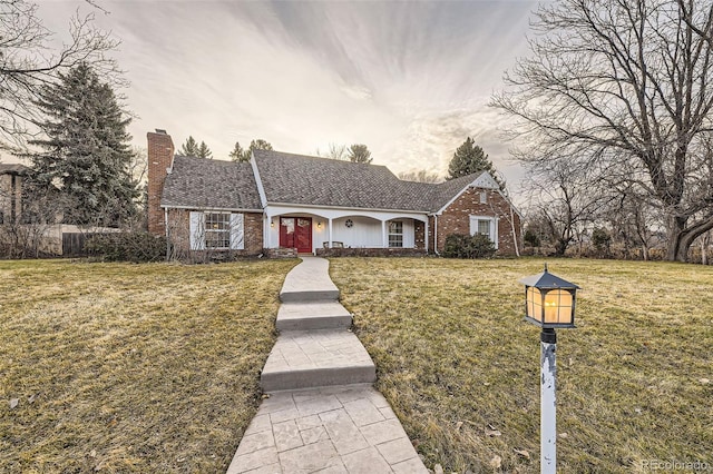 ranch-style home featuring a front yard, brick siding, and a chimney