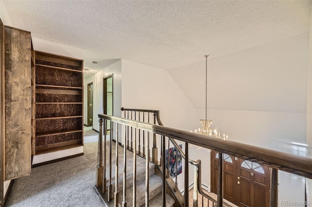 corridor with an inviting chandelier, carpet flooring, vaulted ceiling, a textured ceiling, and an upstairs landing