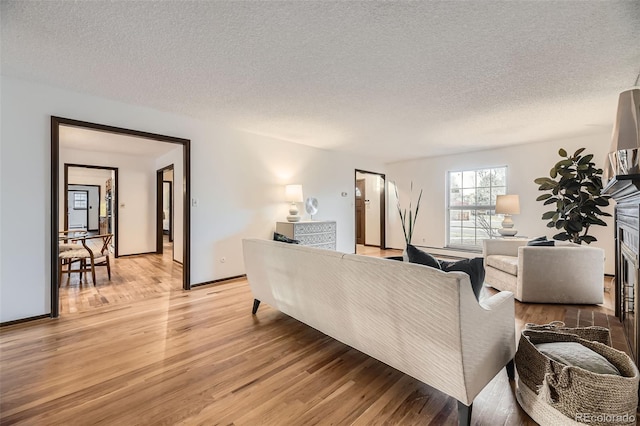 living room with light wood-style flooring, baseboards, and a textured ceiling