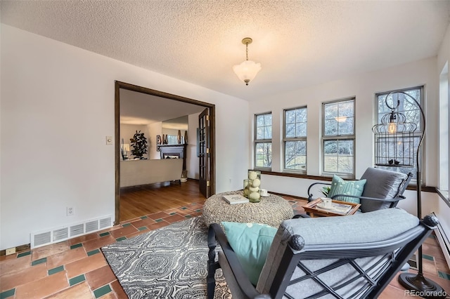 living area featuring baseboards, visible vents, and a textured ceiling