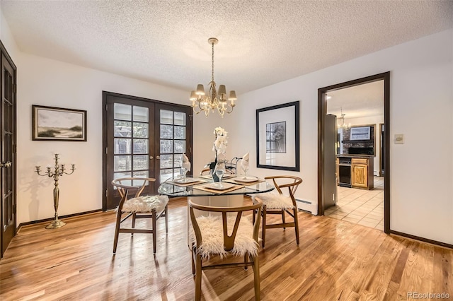 dining space featuring light wood finished floors, french doors, and a notable chandelier