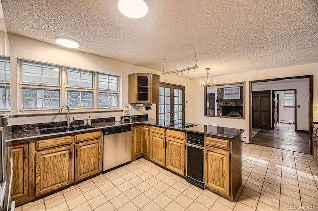 kitchen featuring brown cabinets, a fireplace, a sink, dishwasher, and a peninsula