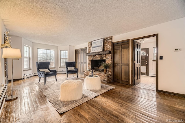 living room with a baseboard radiator, a fireplace, a textured ceiling, and hardwood / wood-style flooring