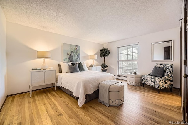 bedroom featuring light wood-style floors, a textured ceiling, and baseboard heating