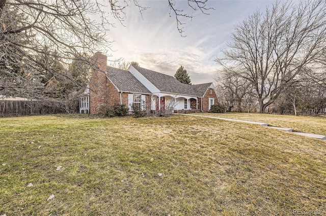 view of front of home featuring a chimney, a front lawn, and brick siding