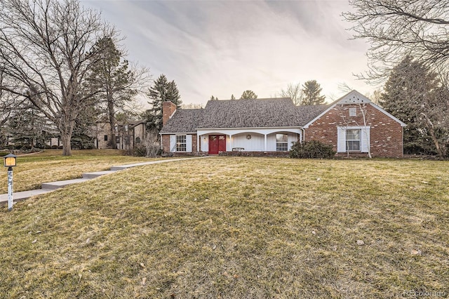 view of front of property featuring brick siding, a chimney, and a front yard