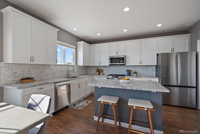 12420 Verbena St, Thornton, CO 80602 - kitchen with stainless steel appliances, a breakfast bar, white cabinets, dark wood-type flooring, and recessed lighting