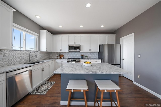 12420 Verbena St, Thornton, CO 80602 - kitchen featuring stainless steel appliances, a kitchen bar, decorative backsplash, white cabinets, and a center island