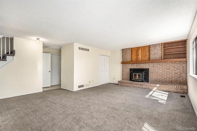 unfurnished living room featuring a fireplace, carpet, brick wall, and a textured ceiling