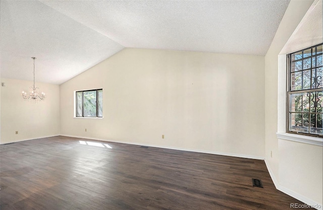 empty room featuring a chandelier, a textured ceiling, dark hardwood / wood-style flooring, and vaulted ceiling