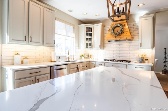 kitchen featuring sink, light stone counters, tasteful backsplash, decorative light fixtures, and appliances with stainless steel finishes